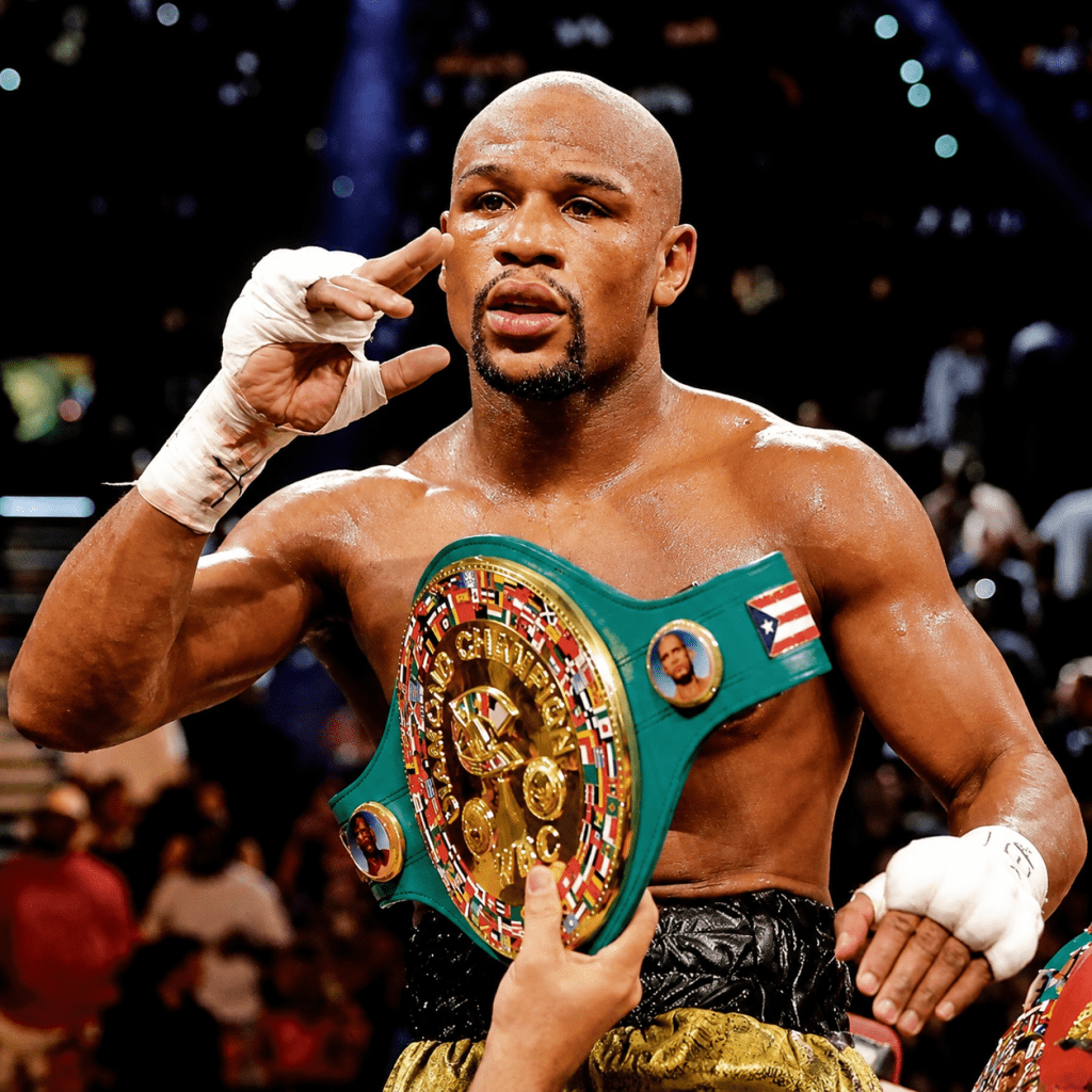 Floyd Mayweather holding a championship belt in the boxing ring for article about felony charges over alleged luxury watch payment