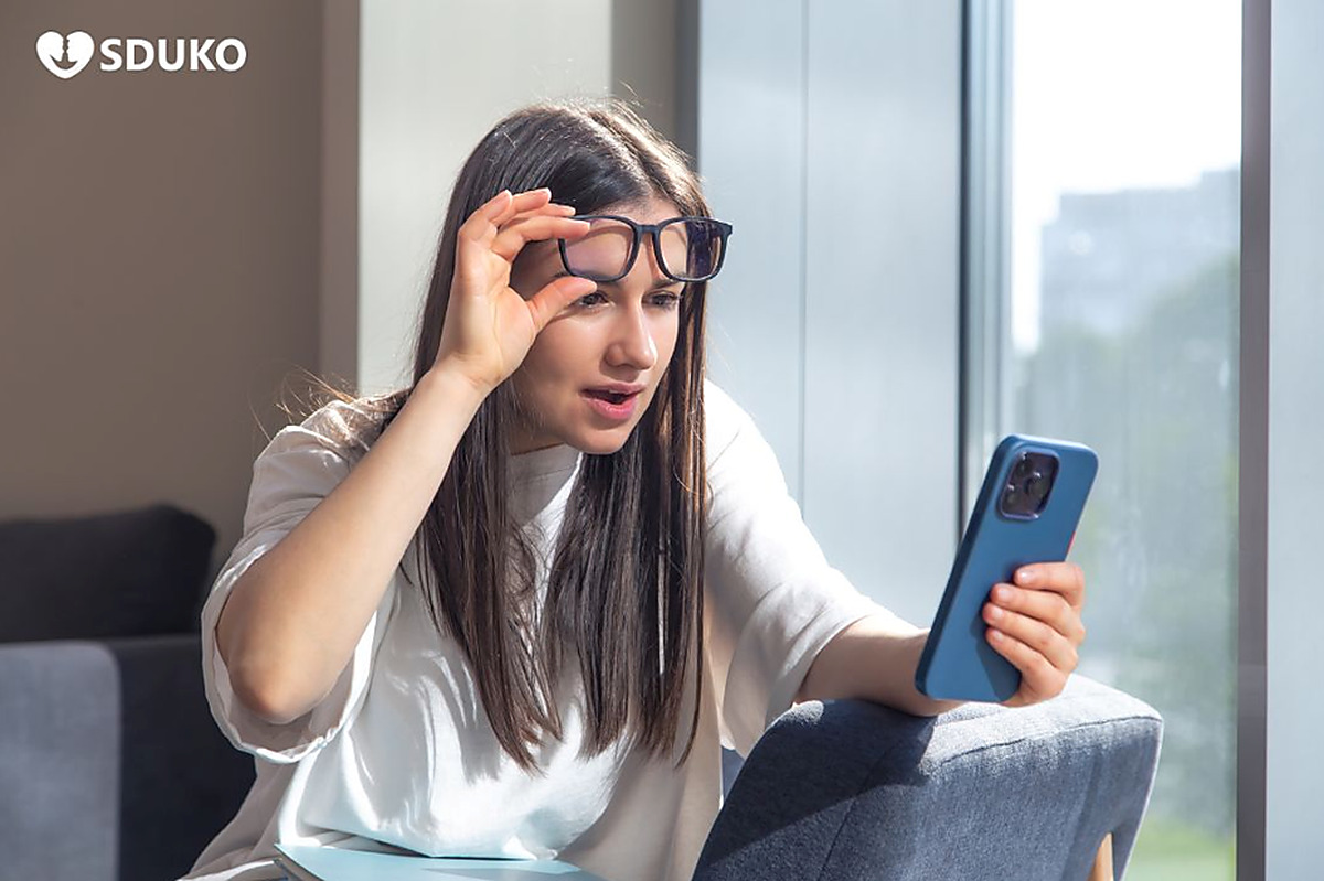 Woman checking her phone while experiencing eye strain with anti-reflective glasses