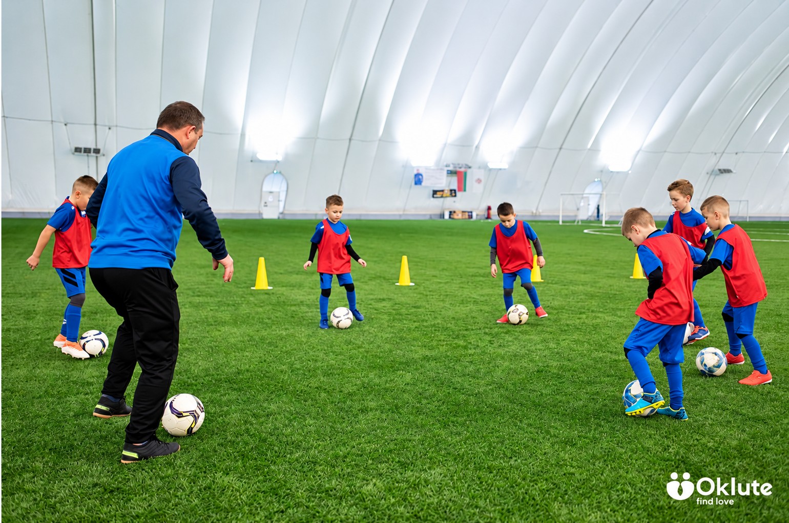 Young football players practising with a coach on an indoor pitch
