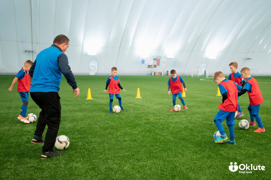 Youth football team practising skills with a coach on an indoor pitch