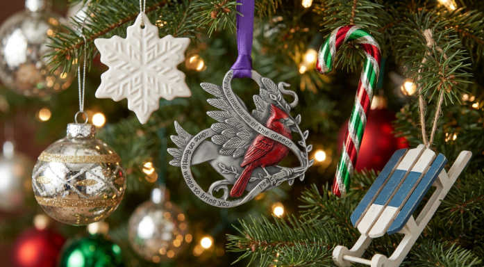 Custom metal cardinal ornament hanging on a Christmas tree with festive baubles and lights